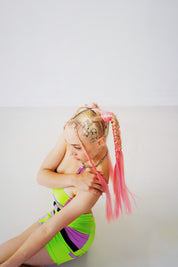 Woman sitting on ground with Roze - Pink Ombre Tinsel Braiding Hair